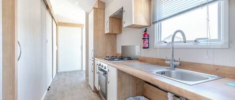 A modern kitchen with a wooden countertop, stainless steel sink, and a window with blinds.