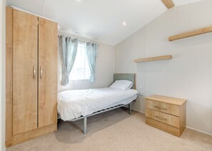 Un dormitorio con cama, armario de madera y mesita de noche.