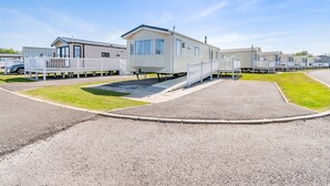 A row of mobile homes with a paved walkway in between. - Gold Caravan 6 WCF (Pet) (Skegness)