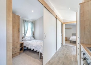 Ein Schlafzimmer mit Bett, Schrank, kleinem Schreibtisch und angrenzendem Badezimmer.