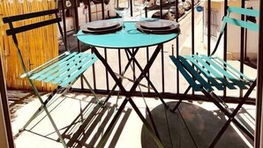 Une terrasse extérieure avec une table ronde et deux chaises, entourée d’une clôture en métal.