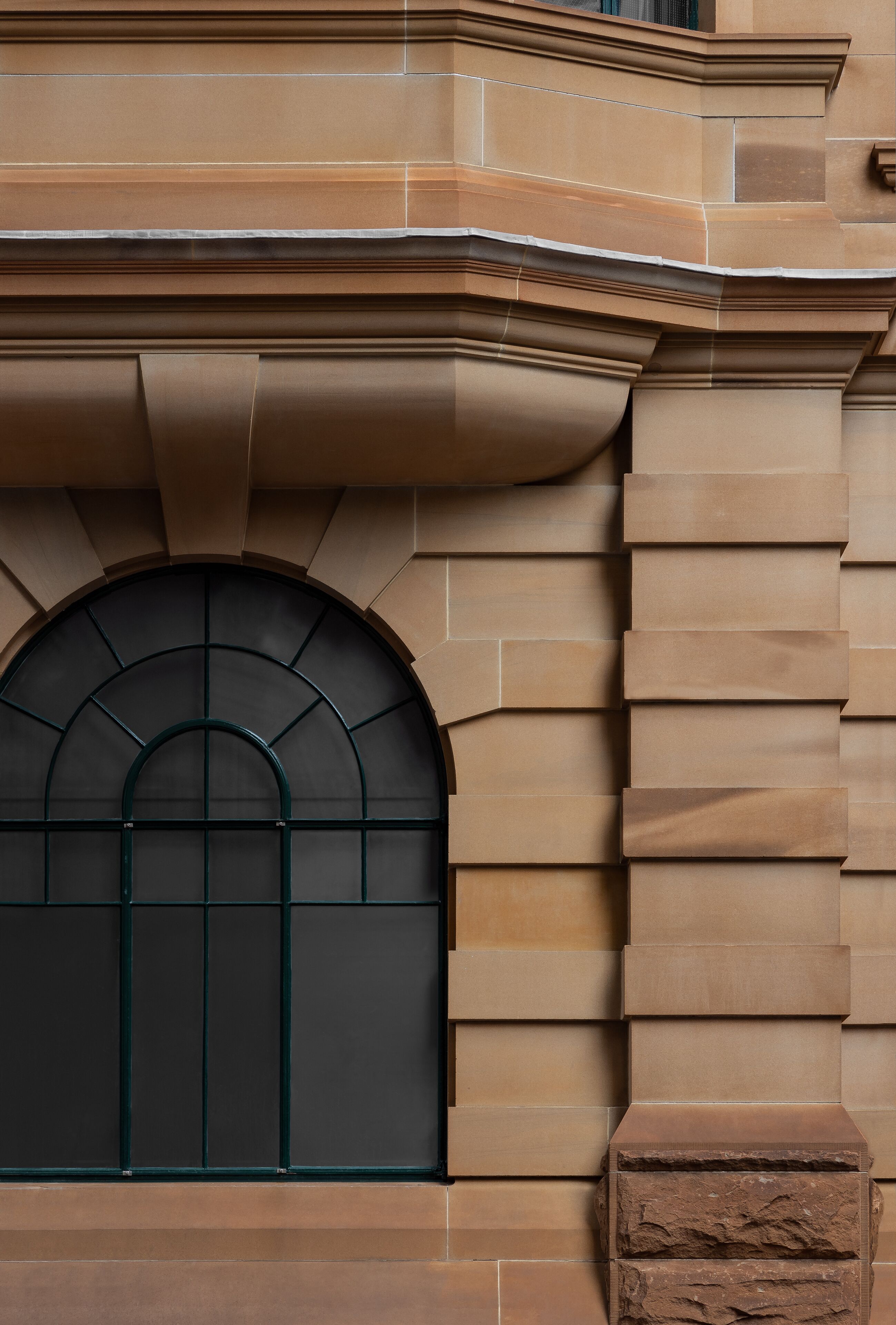 Une façade d’immeuble avec une grande fenêtre en arc et des éléments de maçonnerie en pierre.