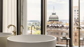 A modern bathroom with a freestanding bathtub, large windows, and a view of a cityscape.