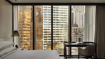 A hotel room with a large window, a bed, a desk, and a chair.