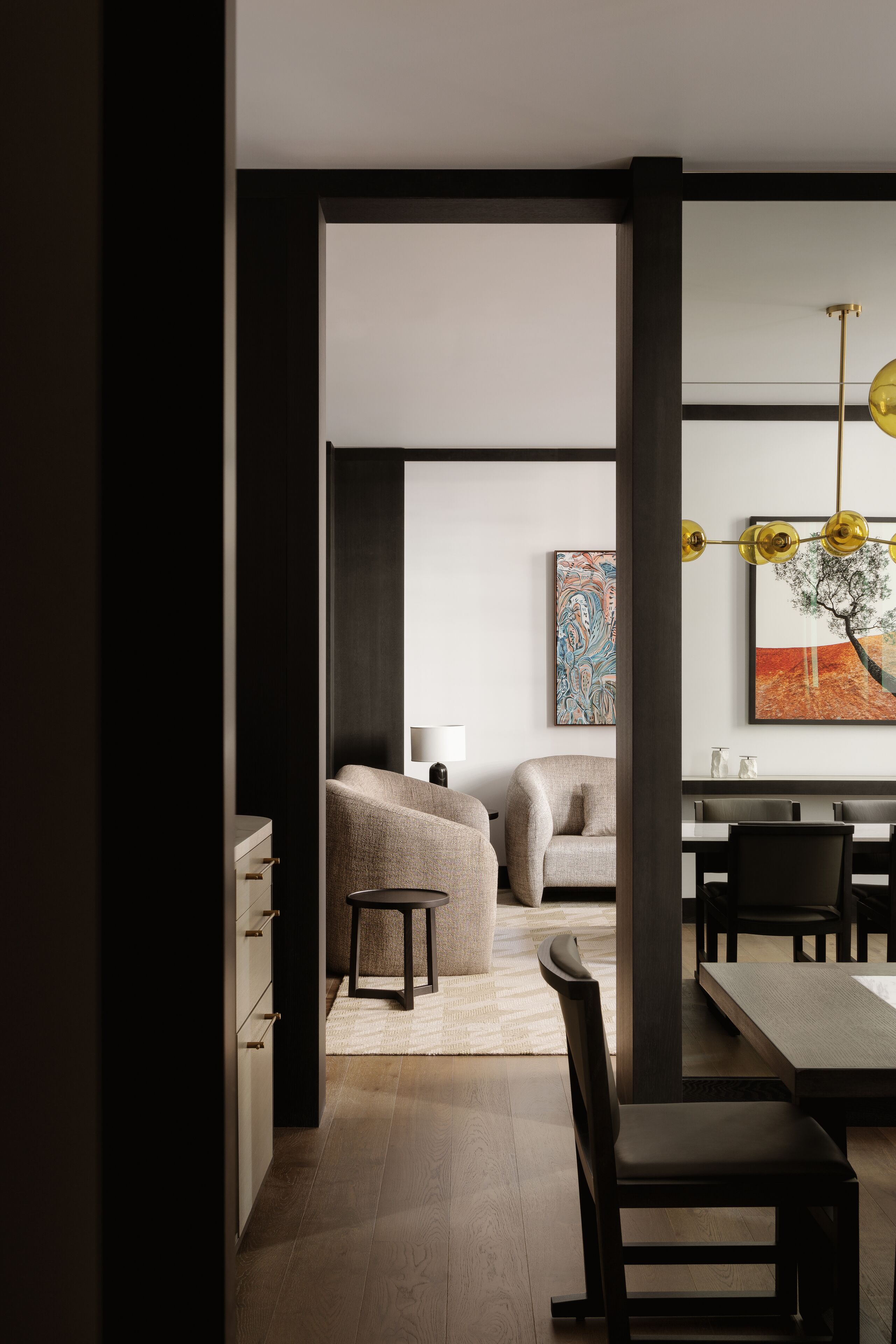 A modern dining area with a wooden table and chairs, a sofa, and a painting on the wall.
