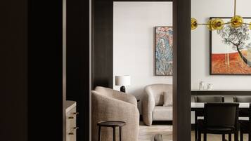 A modern dining area with a wooden table and chairs, a sofa, and a painting on the wall.