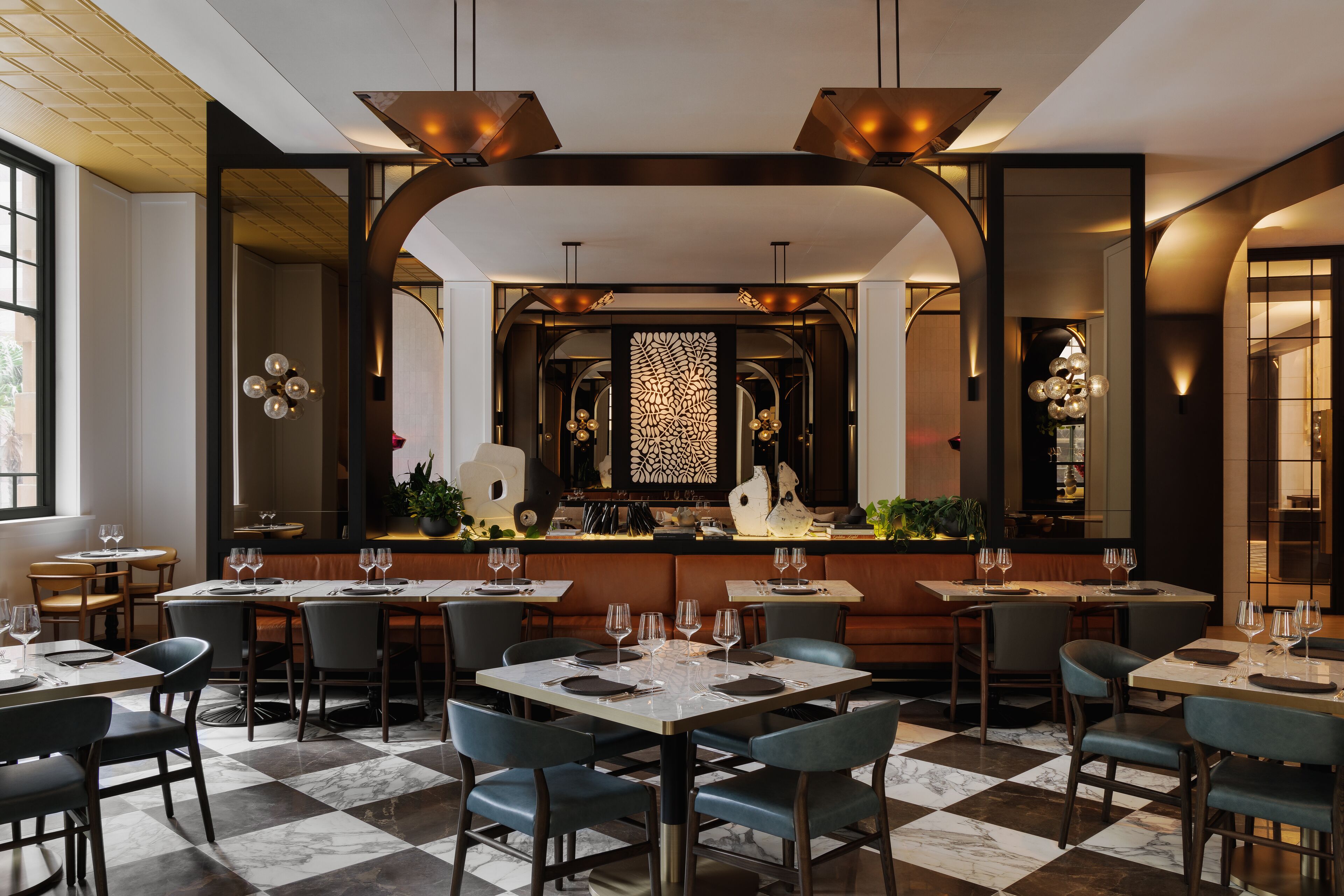 Un intérieur de restaurant moderne avec un sol à carreaux, des chaises aux couleurs sombres et un bar central.