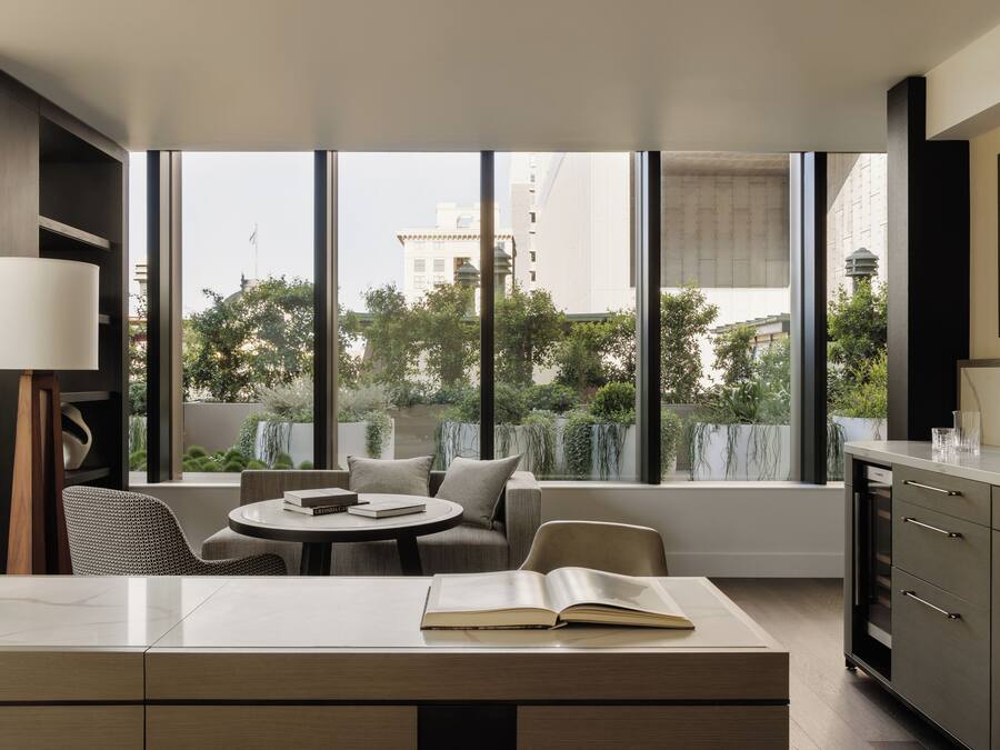 A modern room with a large window, a dining table, a sofa, and a cabinet.