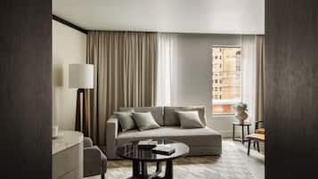 Una sala de estar moderna con un sofá, una mesa de centro, una lámpara y vistas a un edificio a través de una ventana.