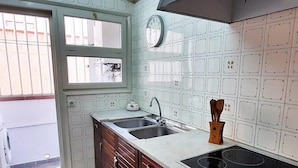 Una cocina con ventana, un fregadero, una estufa y armarios de madera.