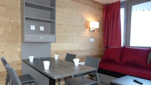 Ett rum med en vägg av trä, ett bord med stolar, en soffa och en lampa.
