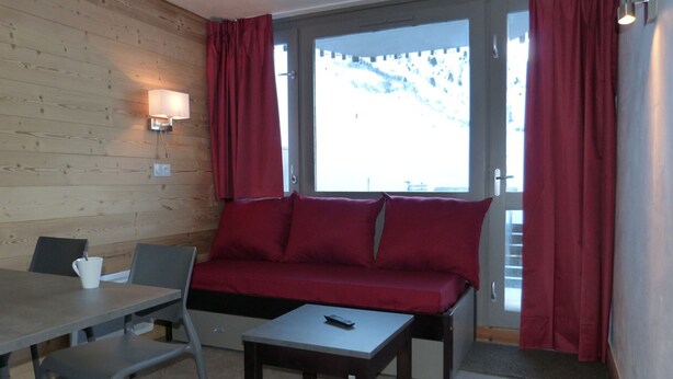 Ett mysigt rum med en väggpanel av trä, en soffa, ett bord och ett fönster med gardiner.