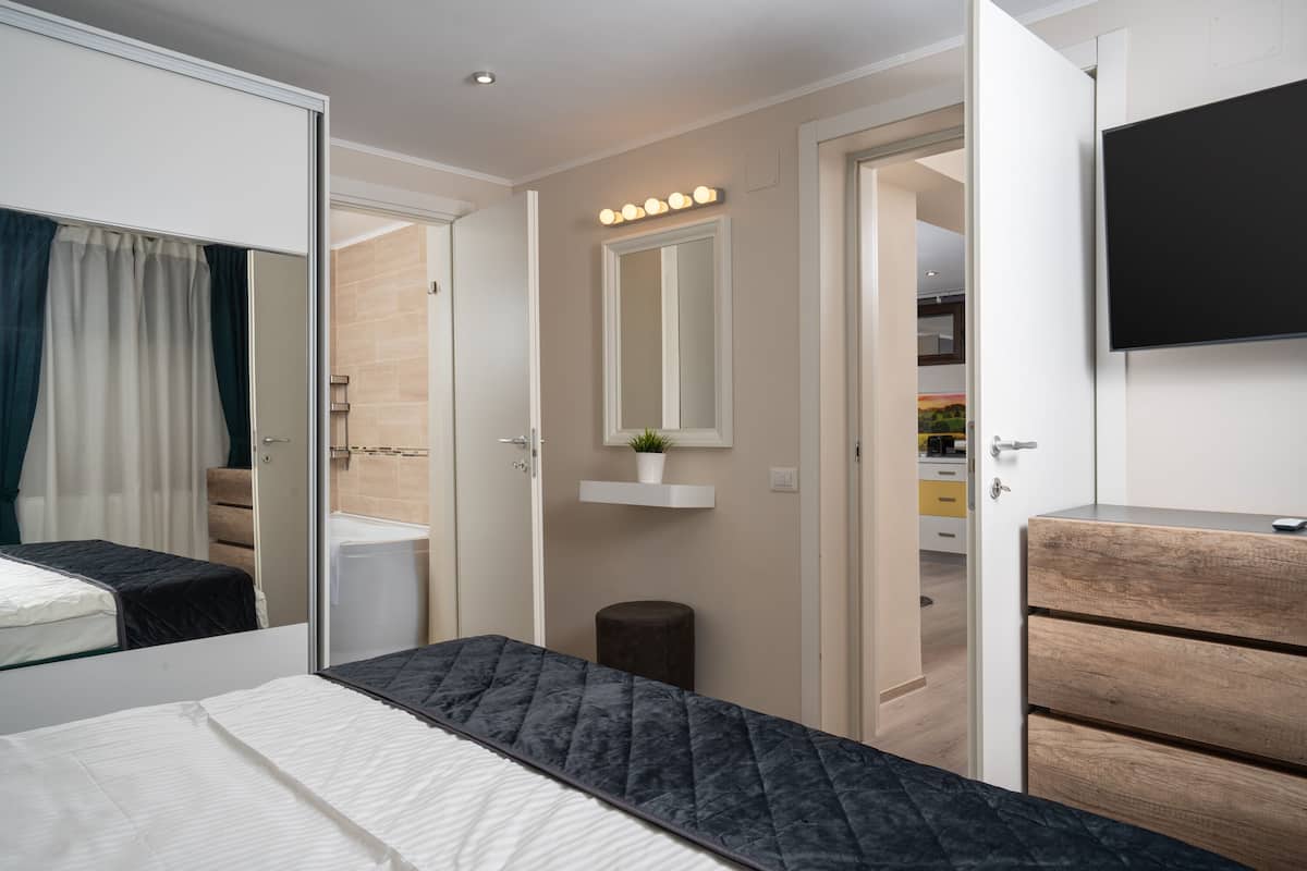Ein Schlafzimmer mit Bett, Kommode, Spiegel und Fernseher.
