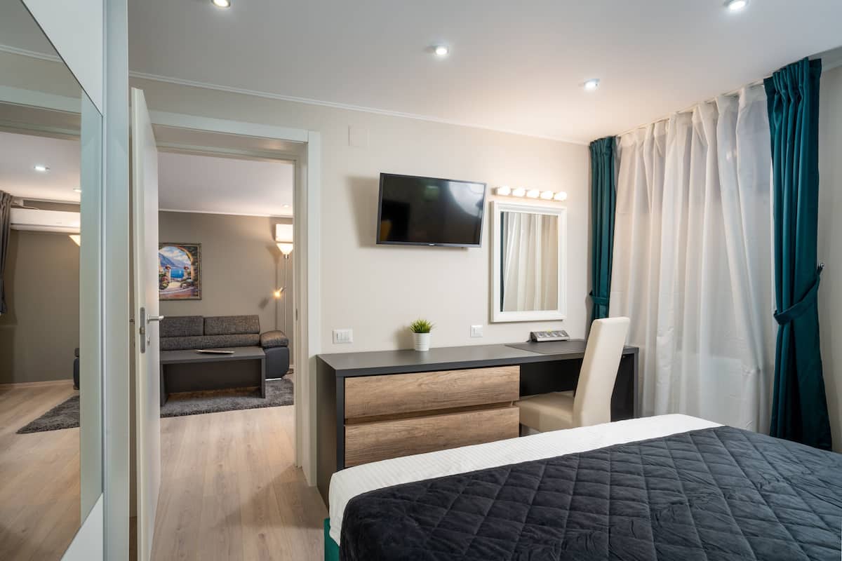 Ein Hotelzimmer mit Bett, Schreibtisch mit Computer, Fernseher und einer Sitzecke mit Sofa und kleinem Tisch.