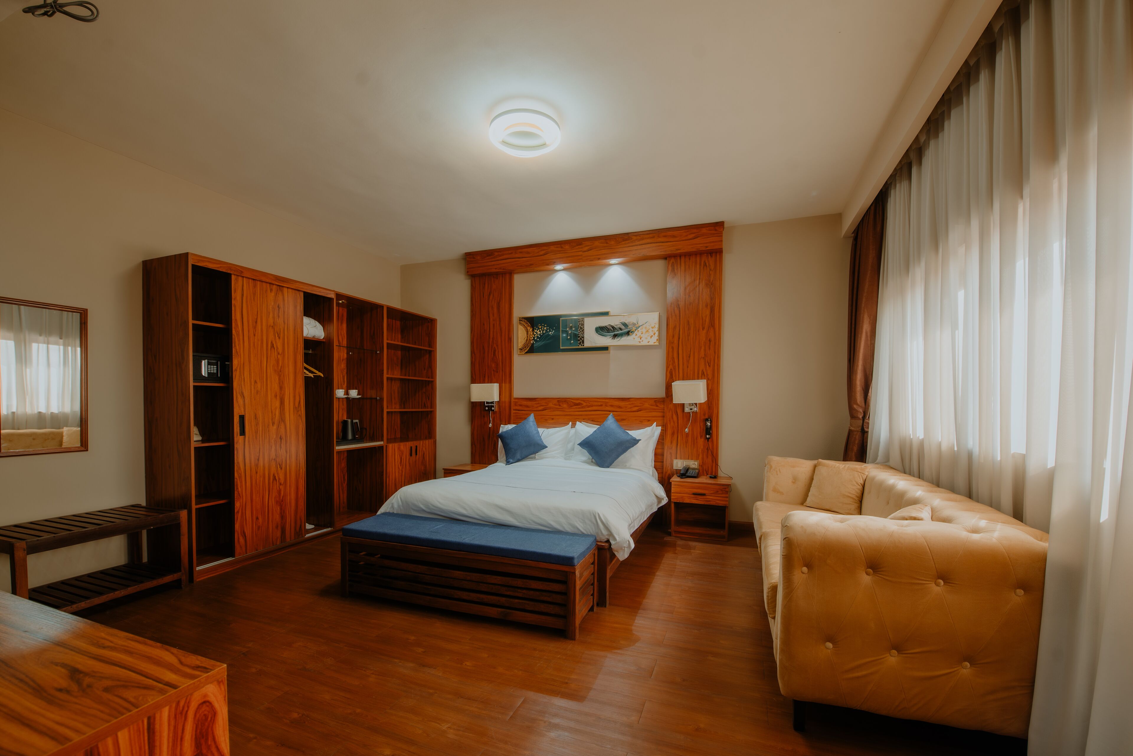 A bedroom with a wooden bed, a wooden bench, a sofa, and a wardrobe.