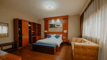 A bedroom with a wooden bed, a wooden bench, a sofa, and a wardrobe.