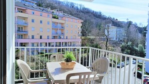 Un balcón con mesa y sillas, con vista a una zona residencial con edificios de varios pisos.