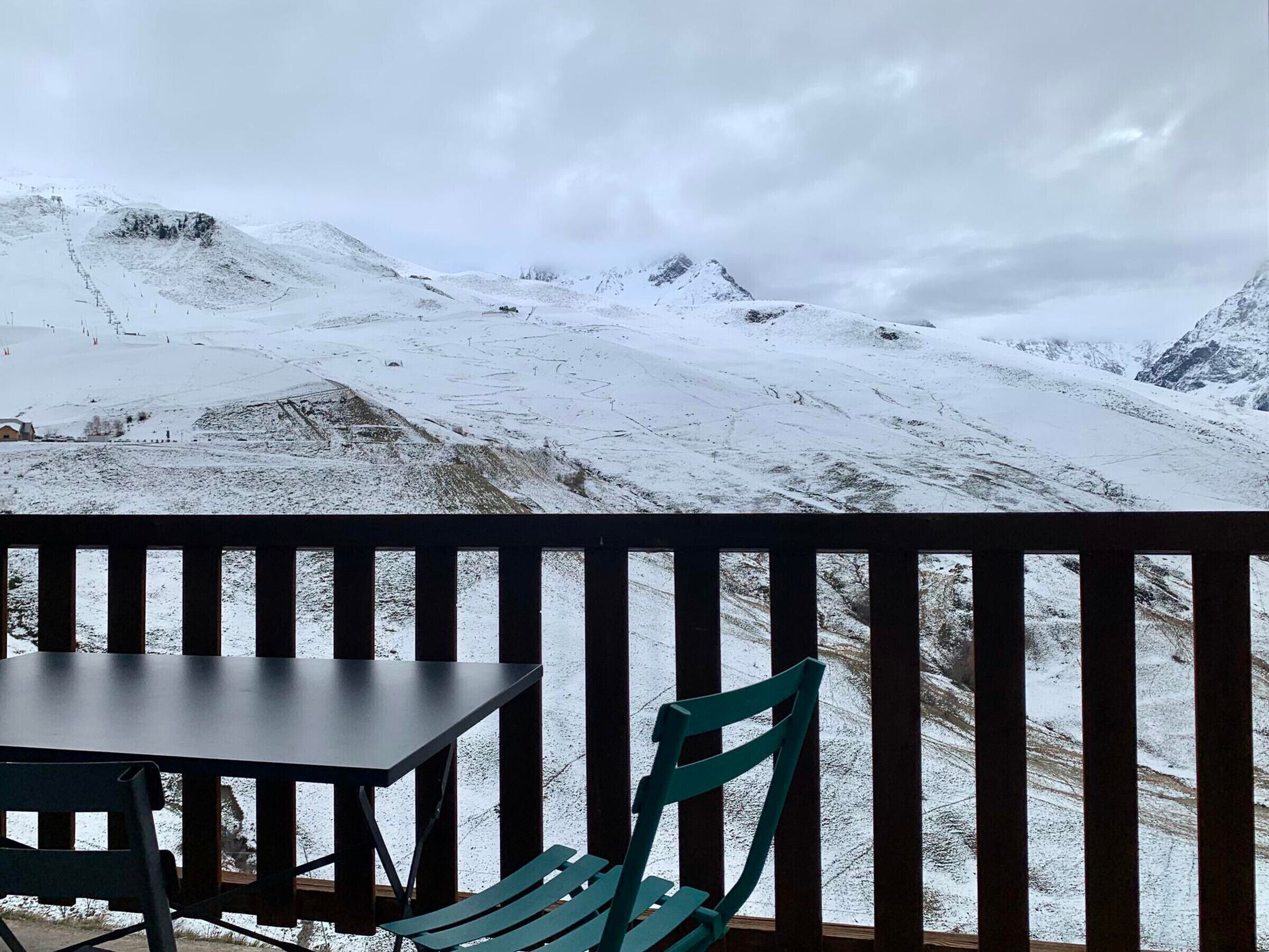 A balcony with a table and chairs overlooking a snowy mountain landscape.