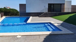 A modern building with a swimming pool and a well-maintained lawn.