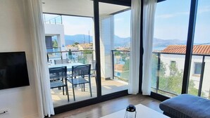 A modern living room with a balcony, a flat-screen TV, a table with a lantern, and a sofa.