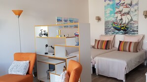 Une chambre avec deux lits, une bibliothèque, un vélo et un tableau accroché au mur.