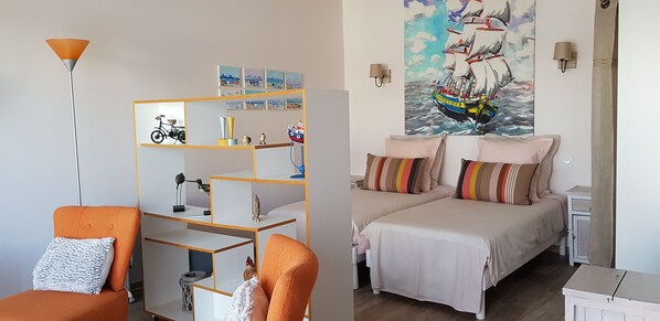 Un dormitorio con dos camas, una estantería, una bicicleta y un cuadro en la pared.