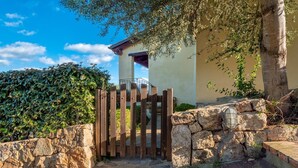 A stone wall, a wooden gate, and a building with a balcony. - APARTMENT WITH SEA VIEW VERANDA 5 MINUTES FROM THE BEACH (Golfo Aranci)