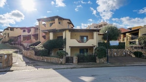 A residential building with a stone wall, a gated entrance, and a clear sky. - APARTMENT WITH SEA VIEW VERANDA 5 MINUTES FROM THE BEACH (Golfo Aranci)
