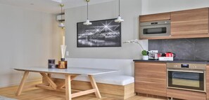 A modern kitchen with wooden cabinets, a built-in oven, and a dining area with a bench and table.