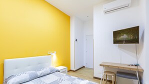 Habitación de hotel con cama, escritorio, silla y televisión en la pared.