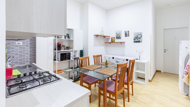 Una cocina moderna con estufa a gas, sillas de madera y una mesa de comedor de vidrio.