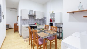 Una cocina compacta con zona de comedor, que incluye una isla central, sillas de madera y una mesa con cubierta de vidrio.