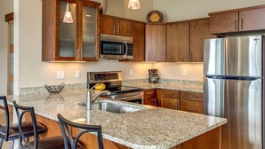 Una cocina moderna con encimeras de granito, electrodomésticos de acero inoxidable y armarios de madera.