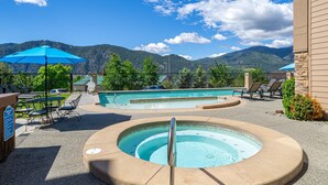 Zona de piscina con jacuzzi, sillas de descanso y sombrillas.