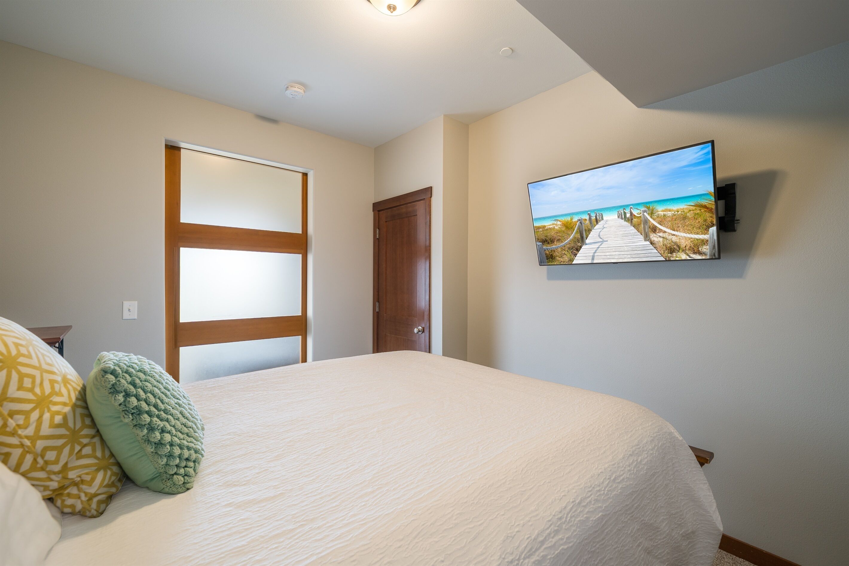 A bedroom with a bed, a television mounted on the wall, and a door.