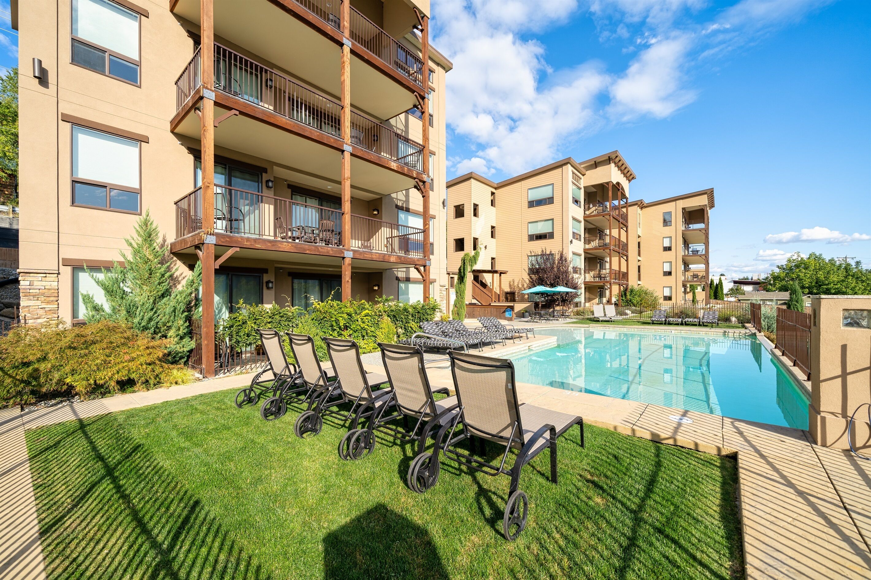 A modern hotel with a pool area, outdoor seating, and a well-maintained lawn.