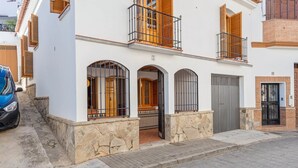 A two-story building with a stone base, a balcony with wooden shutters, and a gated entrance. - Casa Mora + Caminito del Rey (Ardales, Malaga) (Ardales)