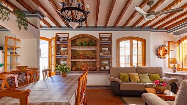 A spacious living room with a dining area, featuring a fireplace, wooden beams, and a chandelier. - Casa Mora + Caminito del Rey (Ardales, Malaga) (Ardales)