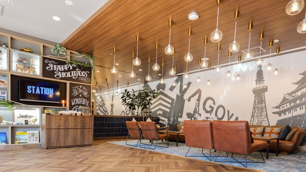 Een moderne lobby met houten vloeren, een receptiebalie, een zithoek en een muur met stadsgezichtsmurales.