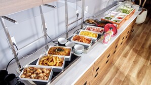 Een buffet met diverse gerechten, zoals hotdogs, eieren en salades.