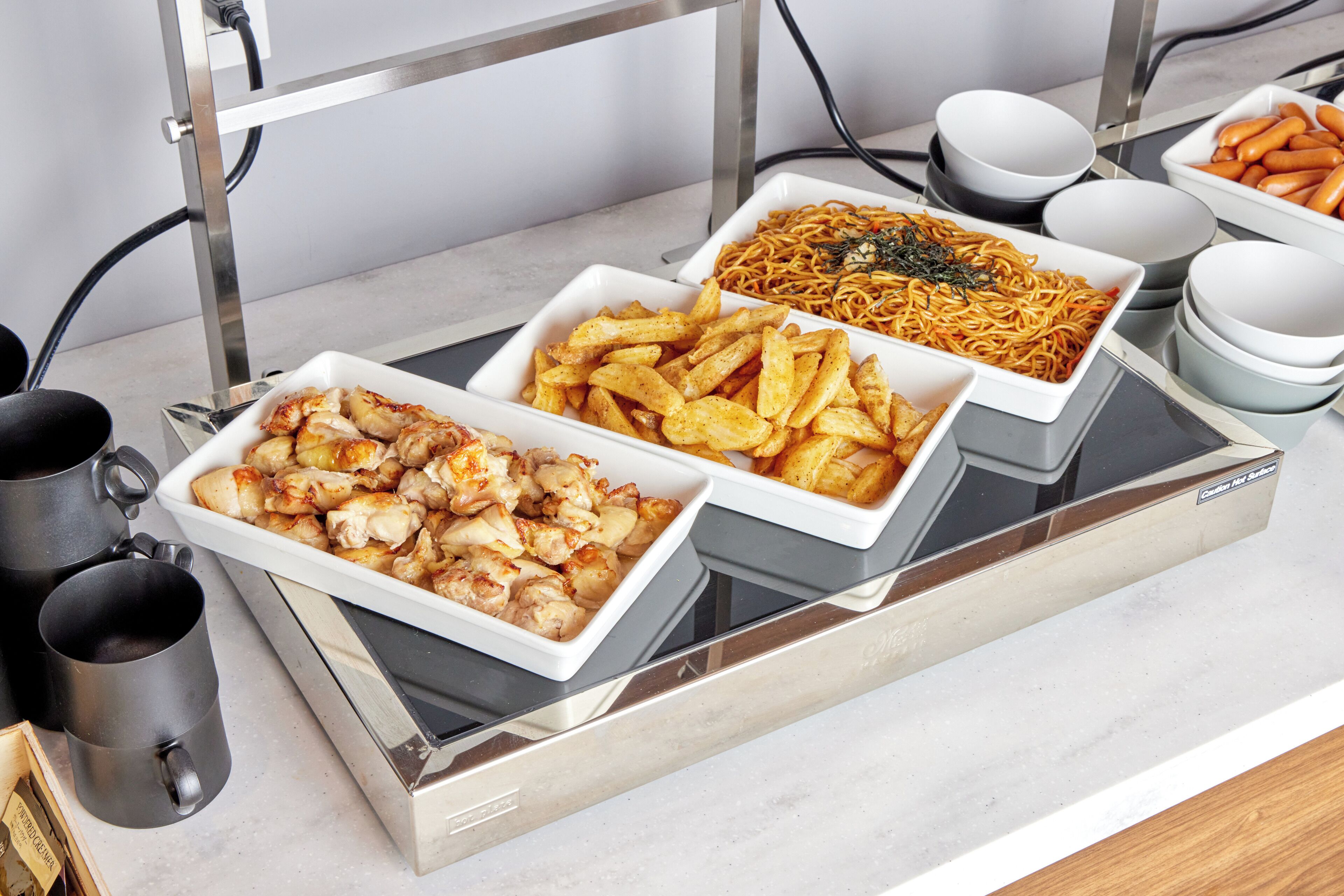 A buffet with various dishes including chicken, fries, and noodles.