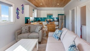 Un espace de vie compact comprenant un coin cuisine, un coin repas et un espace détente avec un canapé et une table.