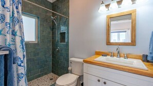 Une salle de bain avec douche, toilettes et lavabo.