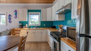 Une cuisine moderne avec des armoires blanches, un pare-feu turquoise, un réfrigérateur en acier inoxydable et un plafond en bois.
