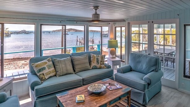 En stue ved kysten med havudsigt, et træbord, en sofa og en lænestol.