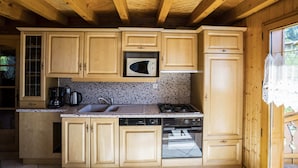 Une cuisine compacte avec des meubles en bois, un four à micro-ondes, une cuisinière à gaz et un lave-vaisselle.
