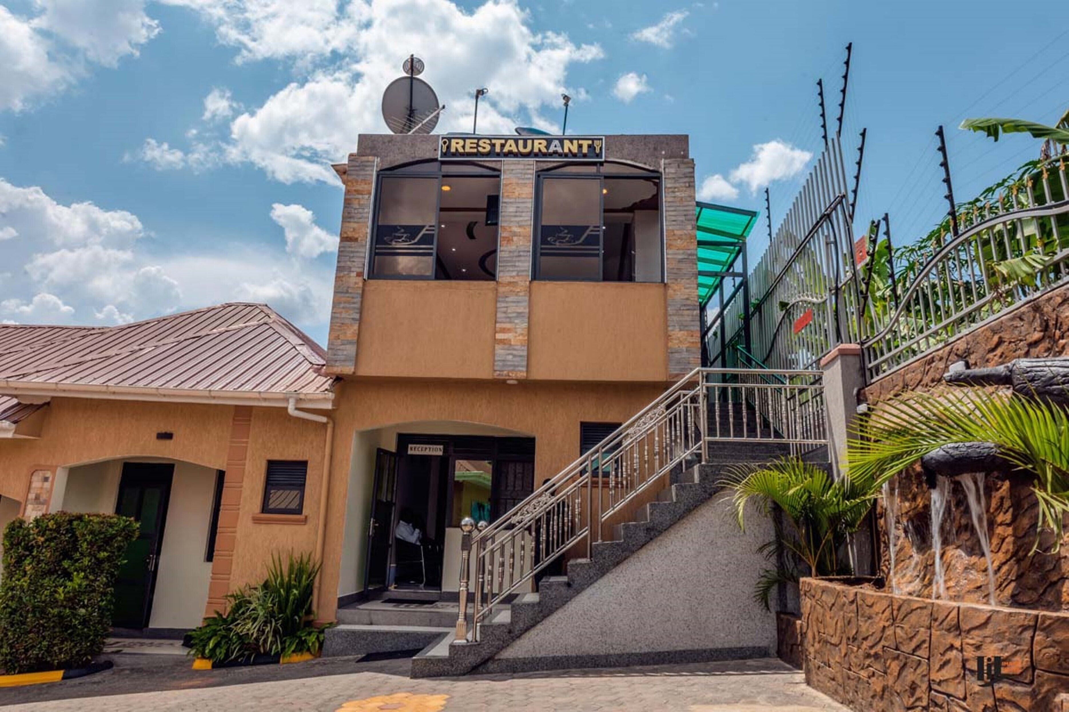 Ein Restaurant mit Empfangsbereich, einer Treppe zum Eingang und einer Steinwand mit Wasserspiel.