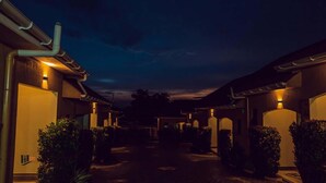 A hotel corridor with traditional architecture, illuminated by warm lighting, and surrounded by greenery. - Imara Hotel (Kampala)