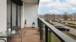 Ein Balkon mit Seeblick, ein Auto auf der Straße und ein Tisch mit Stühlen und einer Laterne.
