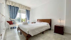 A bedroom with a large bed, a nightstand, a chair, and a window with curtains. - House Pauline 3 Bed. Poolside, Private Garden. M-5 (Marbella)